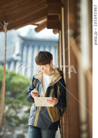 A young male college student looking at a map and searching on his smartphone while traveling to Korea 105845967