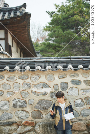 A young male college student looking at a map and searching on his smartphone while traveling to Korea 105845976