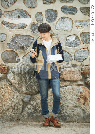 A young male college student looking at a map and searching on his smartphone while traveling to Korea 105845978