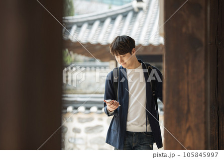 A young male college student looking at his smartphone while traveling to Korea 105845997