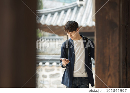 A young male college student looking at his smartphone while traveling to Korea A young male college student looking at his smartphone while traveling to Korea 105845997