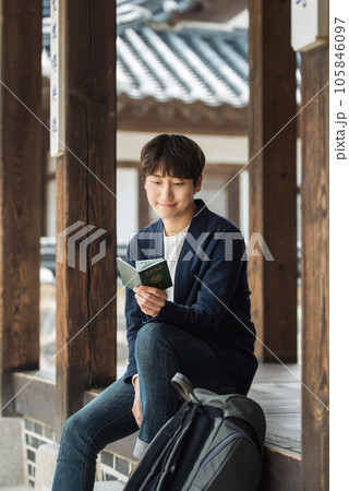 A young male college student sitting and looking at his passport during a trip to Korea A young male college student sitting and looking at his passport during a trip to Korea 105846097
