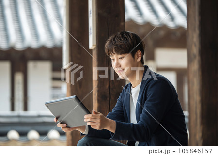 A young male college student sitting and looking at a tablet while traveling in Korea 105846157