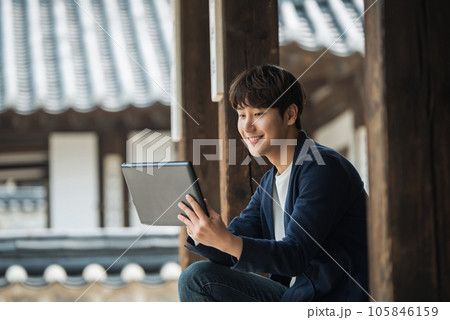 A young male college student sitting and looking at a tablet while traveling in Korea 105846159