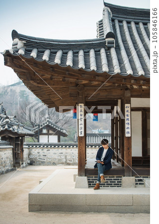 A young male college student sitting and looking at a tablet while traveling in Korea A young male college student sitting and looking at a tablet while traveling in Korea 105846166