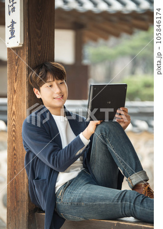 A young male college student sitting and looking at a tablet while traveling in Korea 105846174