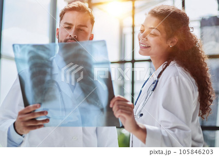 Young serious competent male doctor looking at X-ray at doctor's office Young serious competent male doctor looking at X-ray at doctor's office 105846203