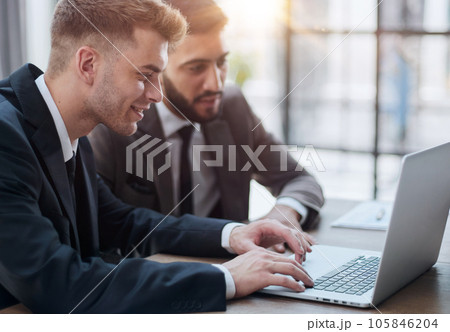 two professional businessmen discussing and using desktop computer in office two professional businessmen discussing and using desktop computer in office 105846204