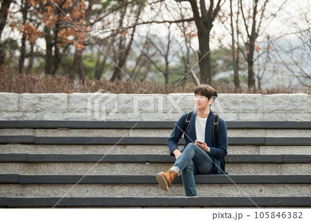 A young man sitting on the stairs looking at his smartphone 105846382
