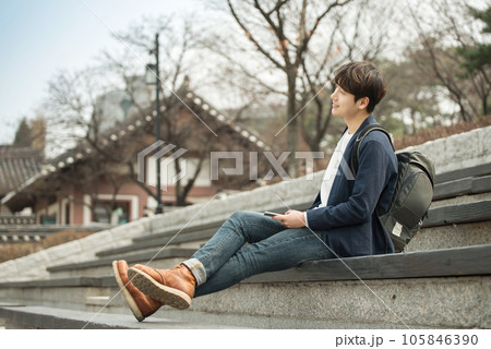 A young man sitting on the stairs looking at his smartphone A young man sitting on the stairs looking at his smartphone 105846390
