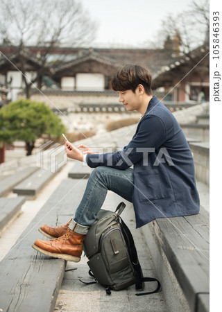 A young man sitting on the stairs looking at his smartphone 105846393