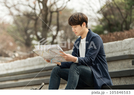 a young man sitting on the stairs looking at a map 105846583