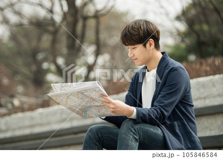 a young man sitting on the stairs looking at a map 105846584