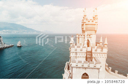 Crimea Swallow's Nest Castle on the rock over the Black Sea. It is a tourist attraction of Crimea. Amazing aerial view of the Crimea coast with the castle above abyss on sunny day. Crimea Swallow's Nest Castle on the rock over the Black Sea. It is a tourist attraction of Crimea. Amazing aerial view of the Crimea coast with the castle above abyss on sunny day. 105846720