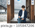 A young man sitting on the stairs looking at his smartphone 105847206