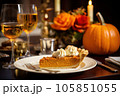 Piece of pumpkin pie revealing a rich golden spiced filling is elegantly served on a rustic wooden table with wine 105851055