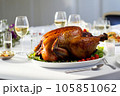 A juicy roast turkey takes center stage on a crisp white dining table in a modern, well-lit dining room 105851062