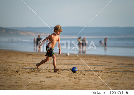 Boy having fun playing running with ball on the beach of Atlantic Ocean. Fonta da Telha beach, Costa da Caparica, Portugal 105851363
