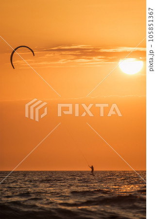 Foiling kiteboarding kitesurfing kiteboarder (kitesurfer) silhouette in the Atlantic ocean on sunset. Fonte da Telha beach, Costa da Caparica, Portugal Foiling kiteboarding kitesurfing kiteboarder (kitesurfer) silhouette in the Atlantic ocean on sunset. Fonte da Telha beach, Costa da Caparica, Portugal 105851367
