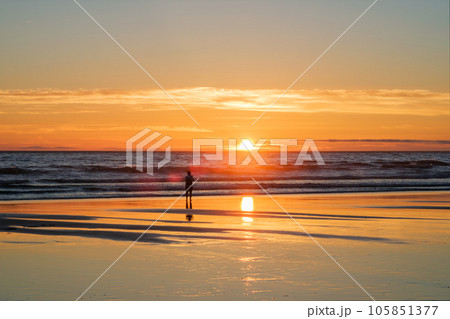 Atlantic ocean sunset with photographer silhouette taking images of surging waves at Fonte da Telha beach, Costa da Caparica, Portugal 105851377