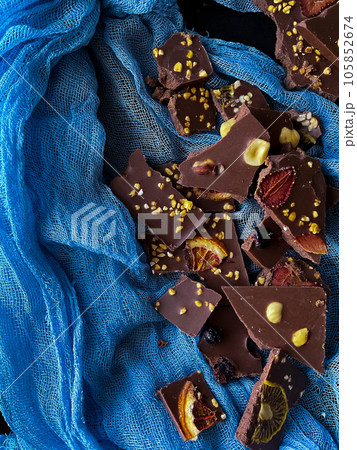 Pieces of homemade chocolate with hazelnuts and nuts on a black background Pieces of homemade chocolate with hazelnuts and nuts on a black background 105852674