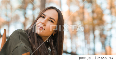 Banner Attractive stylish woman walking in park dressed in warm hoodie copy space. Pretty girl smiles. Autumn urban street fashion style. Fall season 105853143