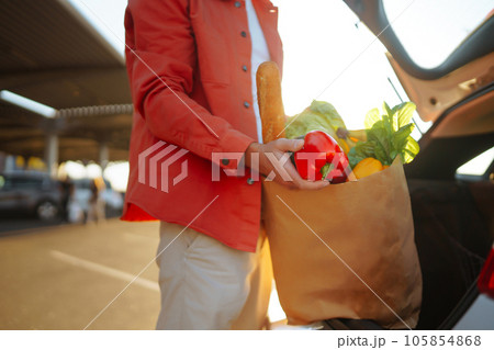 Young man with shopping bag full of vegetables near the car. Handsome man after shopping. Young man with shopping bag full of vegetables near the car. Handsome man after shopping. 105854868