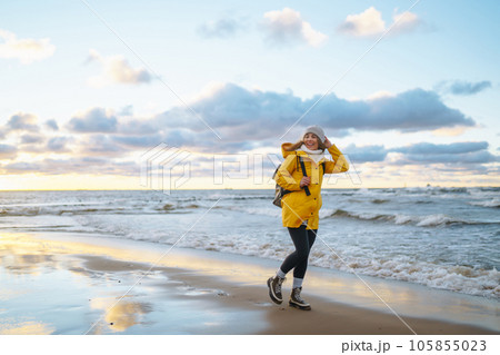 Happy tourist in a yellow jacket enjoying sea landscape at sunset. Travelling, lifestyle, adventure. 105855023