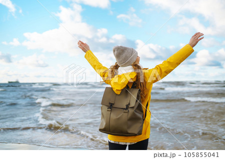 Happy tourist in a yellow jacket enjoying sea landscape at sunset. Travelling, lifestyle, adventure. 105855041