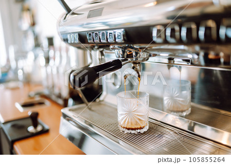 Hot delicious coffee pouring from coffee machine into coffee cup. 105855264