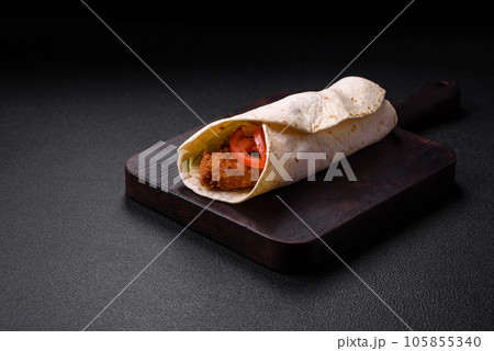 Delicious roll with chicken nuggets, tomatoes, lettuce and sauces with salt and spices 105855340