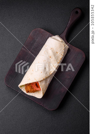 Delicious roll with chicken nuggets, tomatoes, lettuce and sauces with salt and spices 105855342