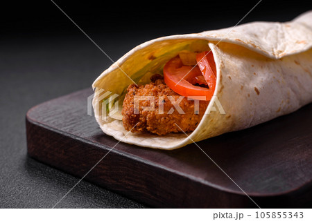 Delicious roll with chicken nuggets, tomatoes, lettuce and sauces with salt and spices 105855343