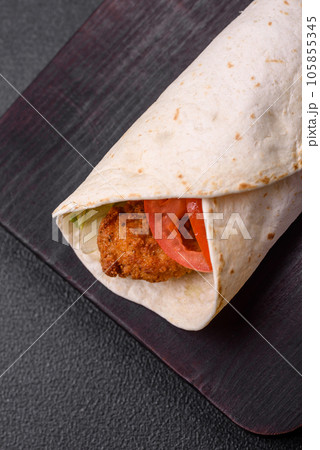 Delicious roll with chicken nuggets, tomatoes, lettuce and sauces with salt and spices 105855345