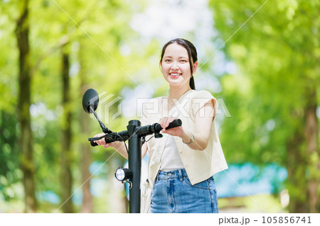 電動キックボードで並木道を走る若い女性 105856741