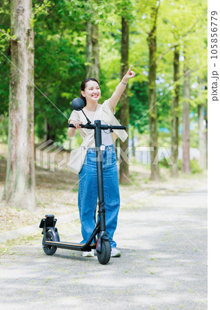 電動キックボードで並木道を走る若い女性 105856779