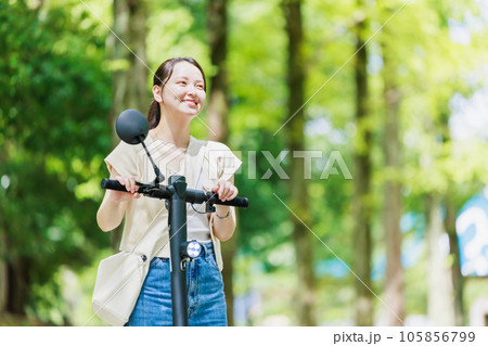 電動キックボードで並木道を走る若い女性 105856799