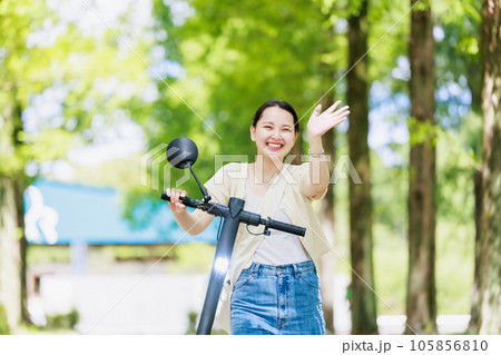 電動キックボードで並木道を走る若い女性 105856810