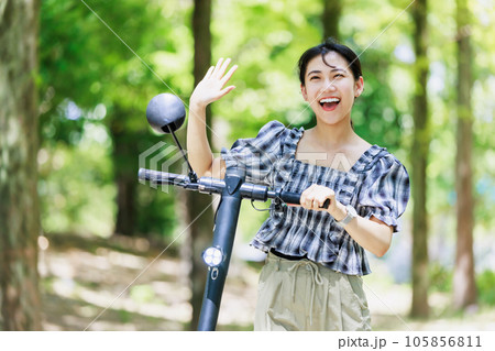 並木道で電動キックボードに乗る若い女性 105856811