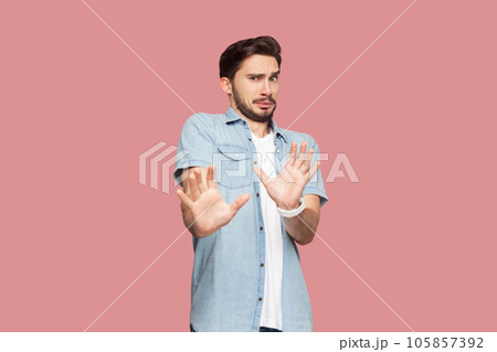 Oh no, stop it immediately. Desperate bearded man in casual style shirt standing keeps palms forward, scared of something terrible, has eyes popped out. Indoor studio shot isolated on pink background. Oh no, stop it immediately. Desperate bearded man in casual style shirt standing keeps palms forward, scared of something terrible, has eyes popped out. Indoor studio shot isolated on pink background. 105857392