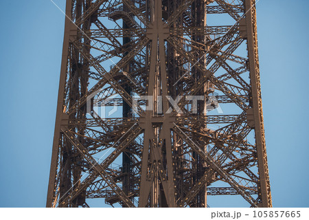 Close up view of the Eiffel Tower in Paris, France with a clear blue sky and green landscape. 105857665