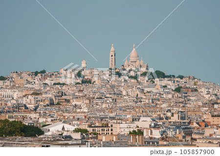 Aerial view of Paris cityscape on a sunny day, with The Basilica of the Sacred Heart of Paris visible among white buildings under a blue sky. Aerial view of Paris cityscape on a sunny day, with The Basilica of the Sacred Heart of Paris visible among white buildings under a blue sky. 105857900