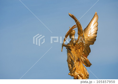 Closeup shot of the Golden Angel of Victoria Memorial. Iconic Symbol of London. Famous sculpture with blue sky on sunny day. Closeup shot of the Golden Angel of Victoria Memorial. Iconic Symbol of London. Famous sculpture with blue sky on sunny day. 105857950