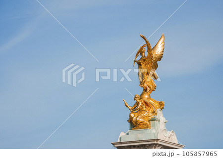 The Angel of Victoria Memorial with blue sky in background. Famous iconic statue of London. Golden sculpture on sunny day. The Angel of Victoria Memorial with blue sky in background. Famous iconic statue of London. Golden sculpture on sunny day. 105857965