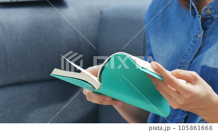 Young asian woman reading book on cozy couch sofa at warm hom. Relax woman holding book read on sofa near window happiness.woman reading open book leisure mind. Happiness woman lifestyle at home 105861668