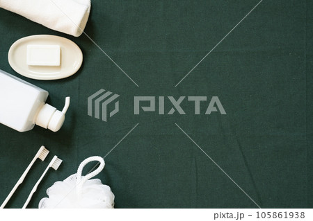 Bathroom white object. shower towel, soap, shampoo dispenser, toothbrush, puff on green fabric background. top view, copy space Bathroom white object. shower towel, soap, shampoo dispenser, toothbrush, puff on green fabric background. top view, copy space 105861938