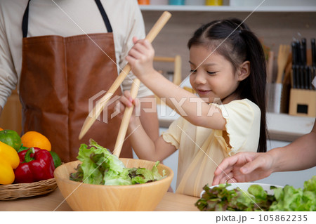 Asian family with father, mother and daughter preparing cooking salad vegetable food together. Asian family with father, mother and daughter preparing cooking salad vegetable food together. 105862235