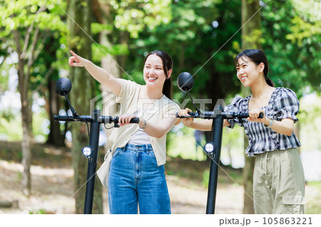 友達と電動キックボードに乗る若い女性 105863221