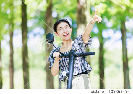 並木道で電動キックボードに乗る若い女性 105863452