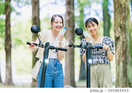 電動キックボードに乗って水分補給する女性 電動キックボードに乗って水分補給する女性 105863453
